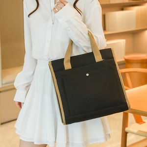 Close-up of canvas tote bag showing beige side panels and silver metallic button detail