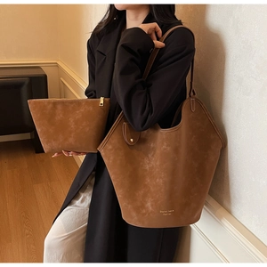 Nahaufnahme der braunen Handtasche aus mattem Leder im Set mit passender Reißverschlusstasche