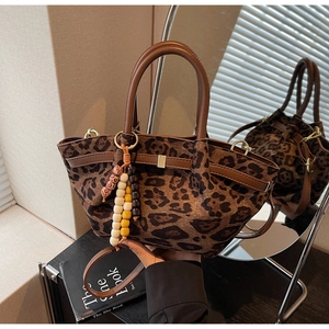 Detail of leopard print bucket bag with matte texture and wooden beaded tassel charm