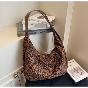 Détail du grand sac cabas en daim léopard avec bandoulière large marron sur des livres