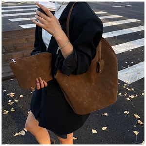 Detail view of retro brown suede tote and matching pouch set in an urban street scene