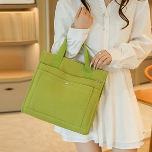 Close-up of a green canvas tote bag with metal buckle detail and front pocket