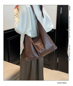 Detailed texture of brown pebbled leather on a vintage minimalist tote bag with vertical stitching