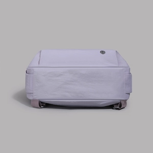 Detail of light purple nylon backpack base with reinforced stitching and logo metal emblem