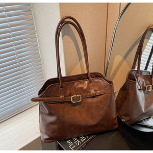 Détail d'un sac cabas en similicuir marron avec texture vintage et boucle dorée