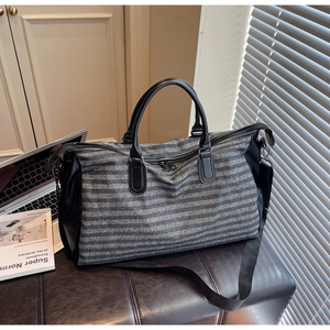 Blue and gray striped travel bag detail showing durable canvas and black PU leather handle