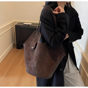 Detailansicht der dunkelbraunen Wildleder-Tote-Bag mit weißen Kontrastnähten und Logo