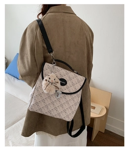 Detail view of beige plaid backpack with cute bunny plush pendant and metal buckle