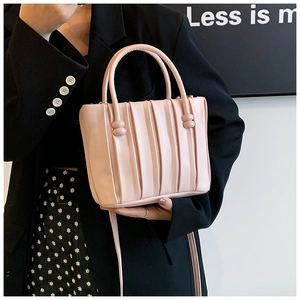 Detail view of pink bucket bag featuring vertical pleats and golden metal zipper