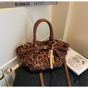 Detail of leopard print bucket bag featuring brown leather handle and wooden bead charm