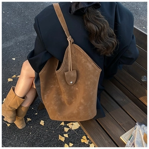 Detail of suede tote bag showing stitching and texture in an outdoor setting