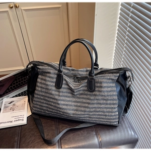 Close-up of striped travel duffle bag with leather handles and detachable shoulder strap
