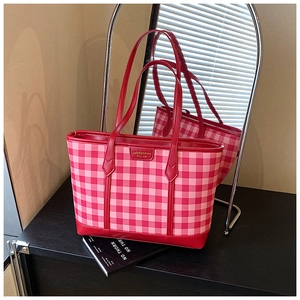 Detail of red gingham pattern and golden metal logo plate on large tote bag
