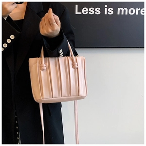 Detail of light pink pleated bucket bag with spherical accent on a black blazer