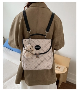 Detail of checkered backpack featuring a metal twist lock and a cute plush bunny charm