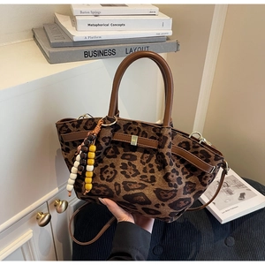 Detail of leopard print bucket bag with brown leather handles and beaded charm accessory
