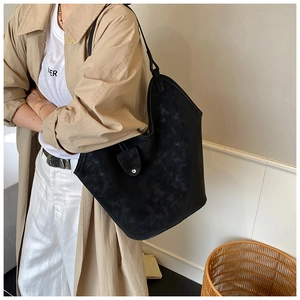Detail of black suede tote bag showing curved top profile and silver button closure