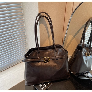 Détail du grand sac cabas marron foncé en cuir avec boucle dorée et texture fine