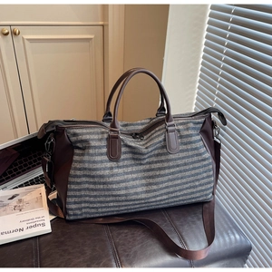 Close-up of durable striped canvas travel bag with leather handles and metal hardware