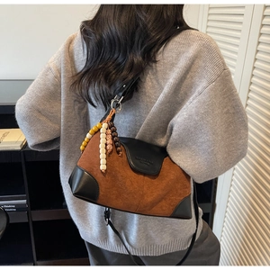 Detail of vintage patchwork shoulder bag with suede textures and beaded charm tassel