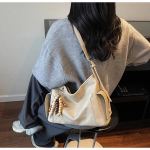 Detail of off-white large capacity tote bag with leather texture and colorful wooden beads