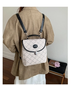 Close-up of beige quilted backpack with plaid pattern, black handle and silver buckle