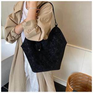 Detail of a minimalist black oversized tote bag with a soft matte texture and metal stud