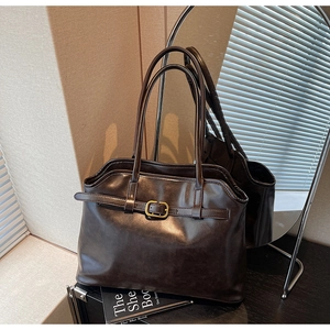 Détail d'un sac cabas en simili cuir marron foncé avec boucle dorée et doubles lanières