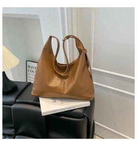 Detail of caramel faux leather tote bag with adjustable strap in minimalist studio setting