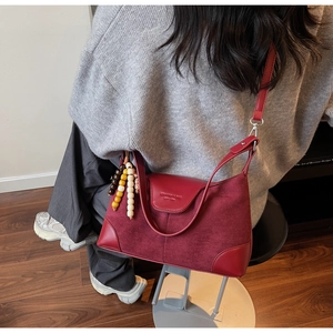Detail of burgundy leather shoulder bag with colorful wooden beads and matte texture