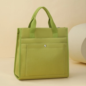 Detail of green canvas tote bag featuring front pocket with silver metal snap button