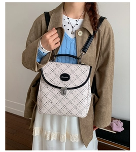 Detail of beige plaid backpack with black leather trim and silver metal buckle closure