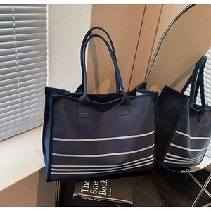 Detail of navy blue canvas tote bag with white stripes and reinforced handles on top