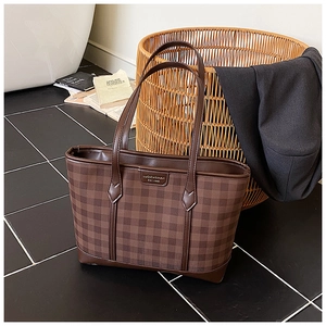 Detail shot of the coffee brown checkered tote bag with branded leather patch and stitching