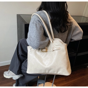 Vue détaillée du sac cabas crème avec boucle élégante et longue bandoulière réglable