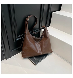 Detail of dark brown vintage hobo bag with oil wax leather texture and adjustable strap