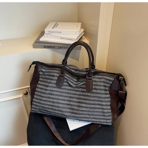 Detail of the gray striped travel duffel with brown leather accents and side compartment
