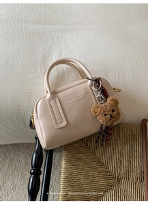 Dettaglio borsa bowling beige in ecopelle con ciondolo a orsetto e sciarpa a quadri