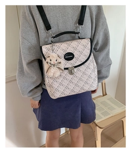 Detail of minimalist plaid backpack with silver buckle and cute white plush bunny charm