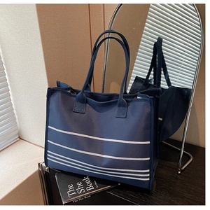 Detail view of navy blue striped canvas tote bag with thick handles and nautical design