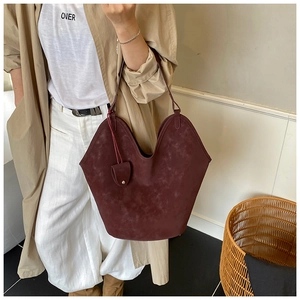 Detail of burgundy suede tote bag with U-shaped cut and matching mini pouch accessory