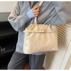 Détail d'un sac cabas beige crème avec une sangle décorative et boucle dorée