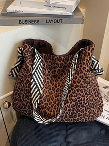 Grand sac cabas léopard avec bandoulières rayées nouées sur une table minimaliste