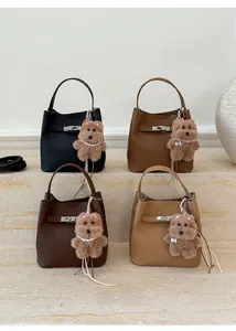 Close-up of leather bucket bags in various colors with metallic clasp and pearl bear charm