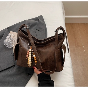Detail of vintage dark brown crossbody bucket bag with colorful wooden bead charm decoration