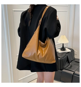 Rear view of a model wearing a large vintage caramel brown faux leather hobo shoulder bag