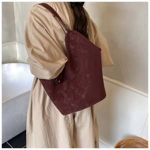 Close-up of deep burgundy suede tote bag showing curved top and elegant metal buckle detail