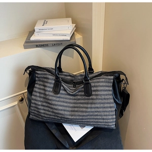 Detailed view of the striped travel bag featuring canvas material and leather handles