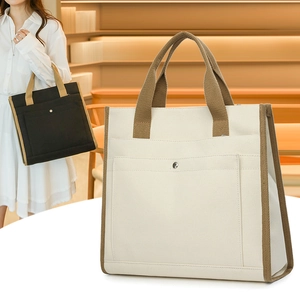 Detail of canvas tote bag showing reinforced brown straps and front pocket with metal snap