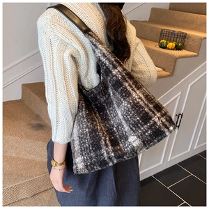 Gros plan d'un sac cabas en laine à carreaux avec bandoulière en cuir noir sur un mannequin